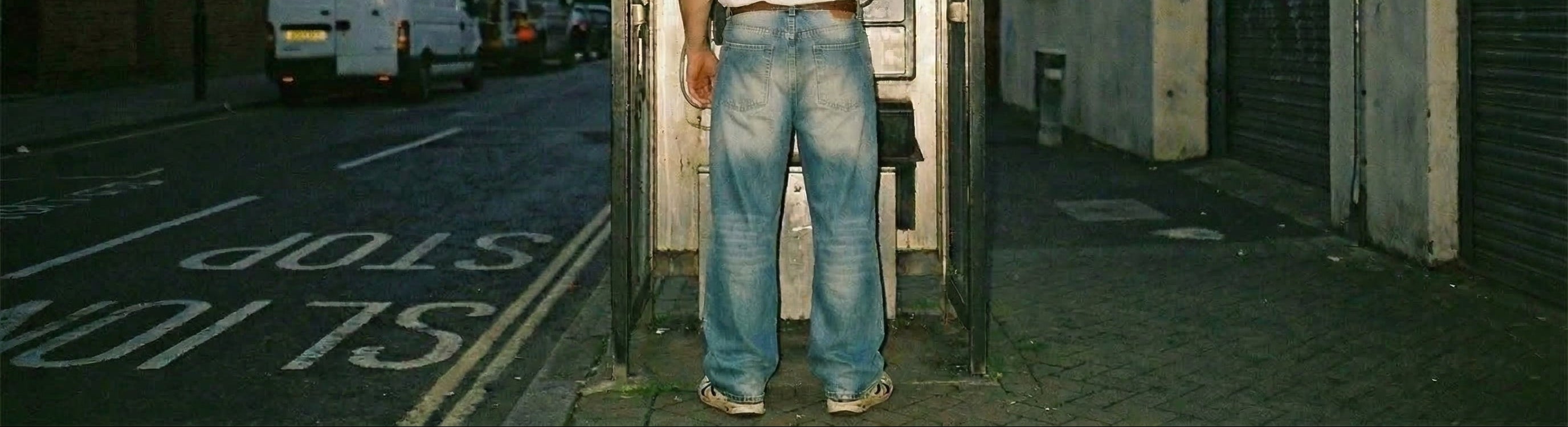 Person standing inside a phone booth on a city street